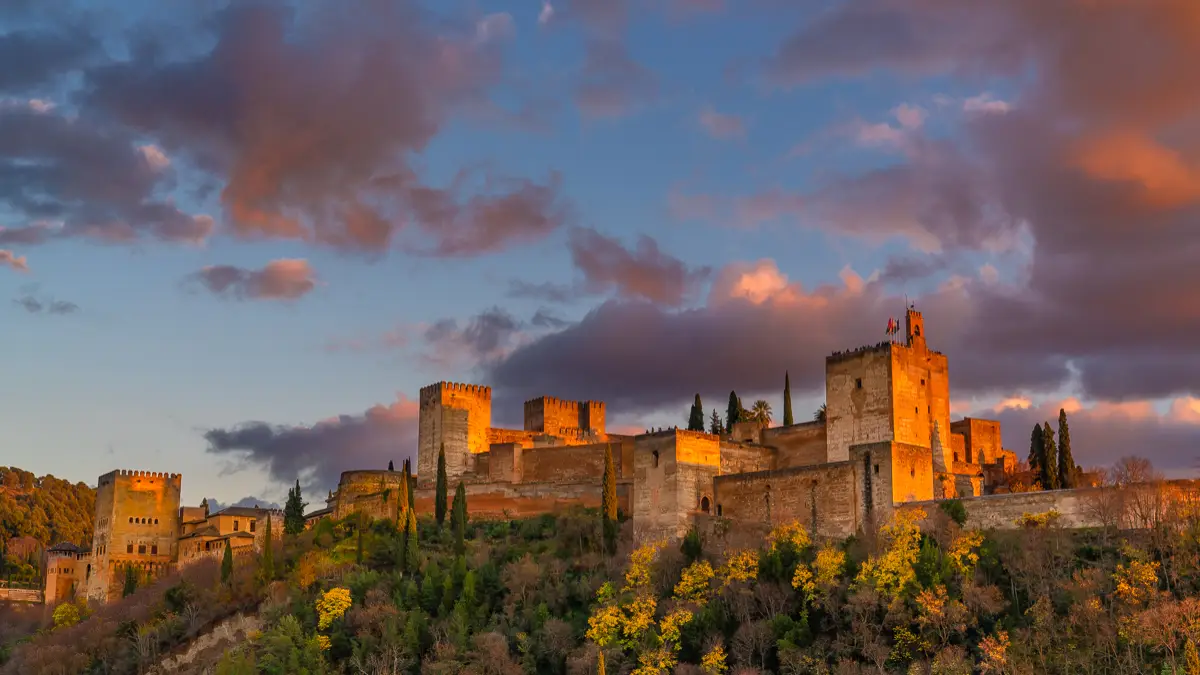 The glowing Alhambra Castle during sunset with pinkish clouds