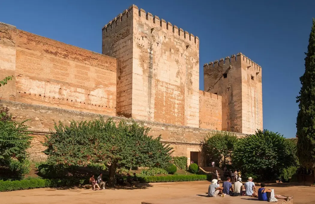 Visitors relaxing in the courtyard near the fortified towers of the Alcazaba