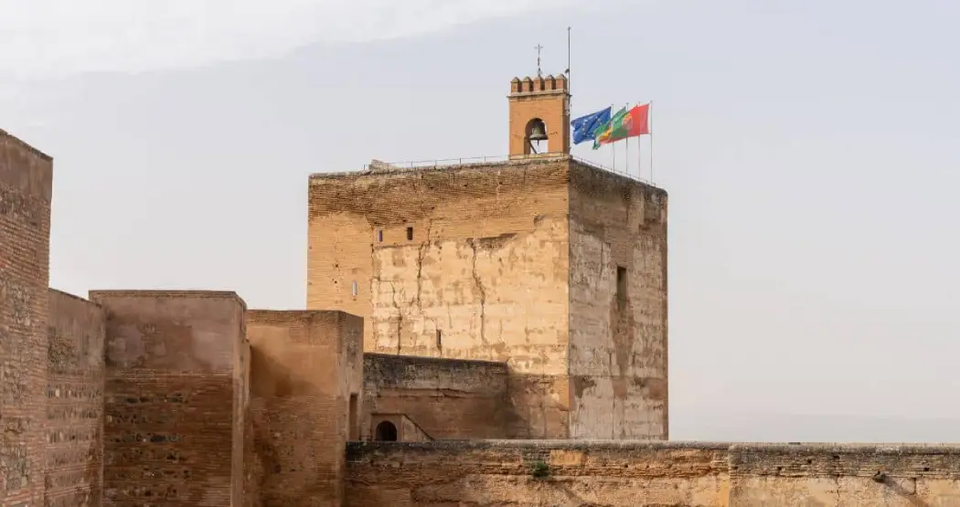 Close-up view of the Torre de la Vela tower at the Alcazaba with flags flying high