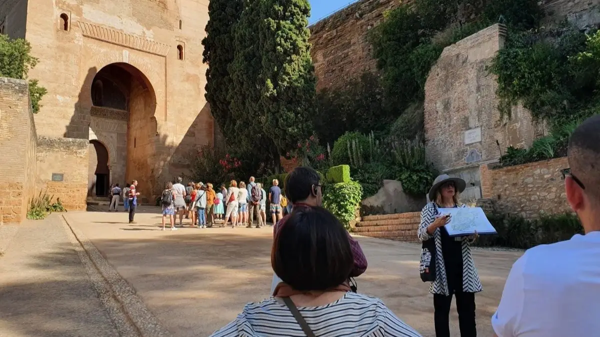 A guide explains the Gate of Justice to the tourists.