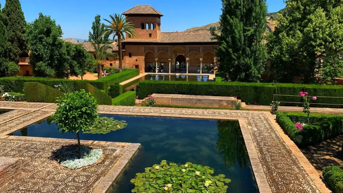 Partal Palace surrounded by trees with an amazing pool in front of it.
